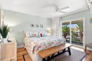 A bedroom with a bed, a ceiling fan, a window with a view, and a small table. - Glimpse the Gulf While Relaxing on H8’s Screened Lanai (Sanibel)