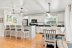 A modern kitchen with white cabinetry, a central island, and pendant lighting. - Glimpse the Gulf While Relaxing on H8’s Screened Lanai (Sanibel)