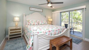 A bedroom with a bed, bedside tables, a ceiling fan, and a view of the outdoors. - Fully Renovated Serene 2/2 ground floor Oasis (Sanibel)