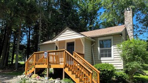 A two-story house with a wooden staircase leading to a front porch. - Private & Relaxing backyard Hot Tub, Fire pit, nap under the trees in a Hammock (Canadensis)