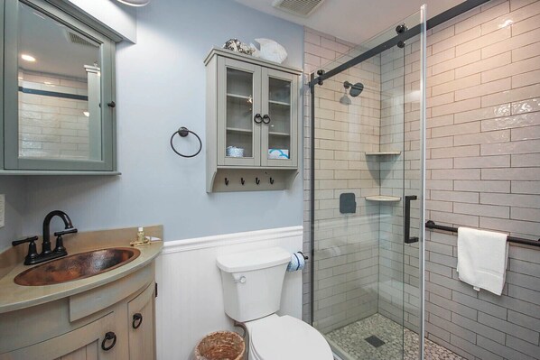 Ein Badezimmer mit Waschbecken, Toilette und Duschkabine aus Glas.