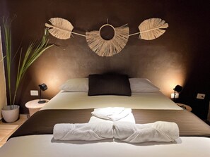 A neatly made bed with white linens, a dark headboard, and a wall-mounted decorative item above it.