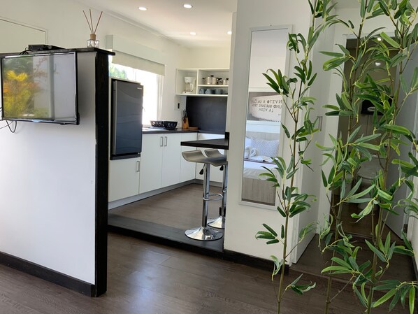 Una cocina moderna con armarios blancos, un refrigerador negro y un taburete de bar.