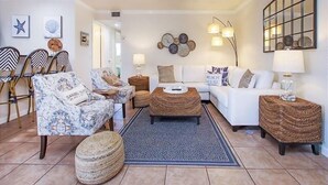 Un salon comprenant un canapé, des fauteuils, une table basse et un coin repas avec des chaises et une table.