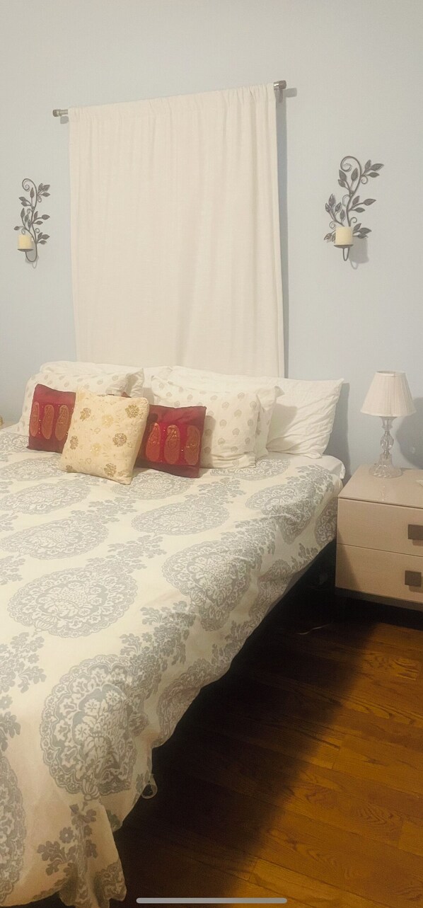 A bedroom with a bed, pillows, a nightstand, and a lamp.