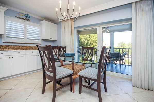 A dining area with a glass table, dark wooden chairs, and a chandelier. - Relax in Peaceful Paradise Five Minutes From the Beach (Sanibel)