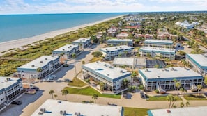 A coastal hotel with multiple buildings, a beach view, and a parking area. - K8 Paradise with a Partial Gulf View (Sanibel)