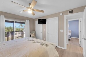 Una camera da letto con un letto, una ventola a soffitto, una TV e un balcone con vista.