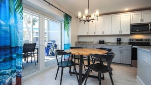 A modern kitchen with white cabinets, a wooden dining table, and black chairs. - Cozy Unit L3 · Sanibel Arms West Condo | Quick 2 Minute Walk to the Beach (Sanibel)