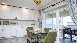 A modern kitchen with white cabinets, a glass dining table, and chairs.