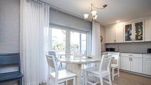 A modern kitchen with white cabinets, a glass dining table, and a chandelier. - Relax in Peaceful Paradise Unit M3 Steps to the Beach (Sanibel)