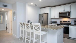 Une cuisine moderne avec des meubles blancs, des appareils en acier inoxydable et un plan de travail en granit.