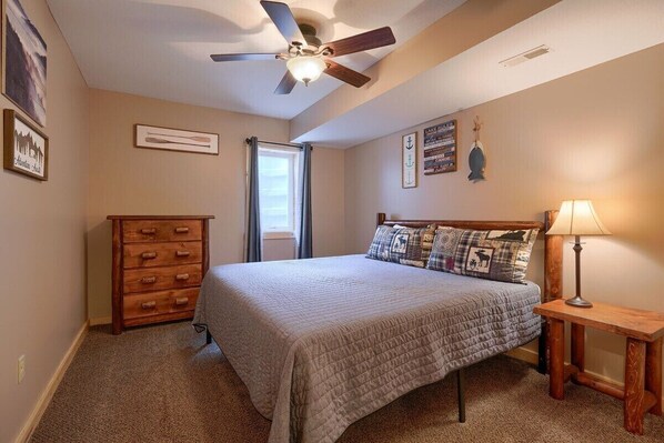 Une chambre à coucher comprenant un lit, un ventilateur de plafond, une commode, une lampe et des éléments décoratifs sur les murs.