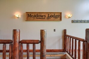 Une enseigne en bois portant l’inscription « Meadows Lodge, fondé en 2011 » est fixée au-dessus d’un escalier dont les rampes sont également en bois.
