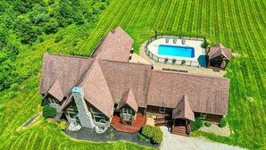 Une grande maison à plusieurs étages, dotée d’une piscine, entourée d’une pelouse et d’un jardin bien entretenus.