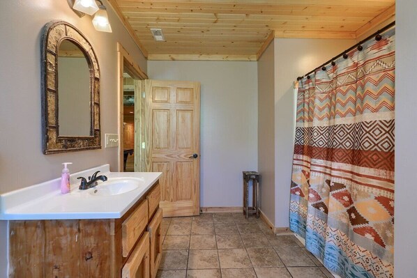 A bathroom with a wooden vanity, a mirror, a sink, and a shower curtain.