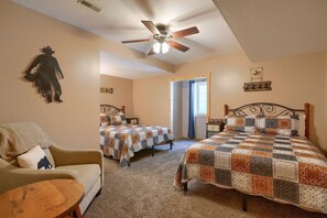 A bedroom with two beds, a ceiling fan, and a cow-themed wall decoration.