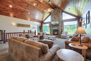 A cozy lodge interior with a stone fireplace, leather sofas, and a wooden ceiling.