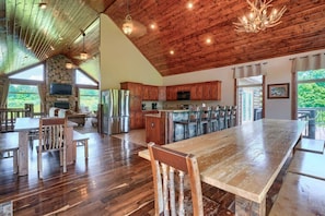 A spacious kitchen with wooden cabinets, a large island, and a stone fireplace.