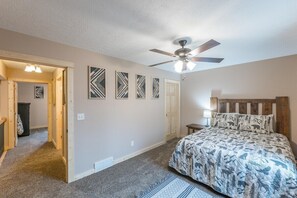 A bedroom with a bed, a ceiling fan, and a door.