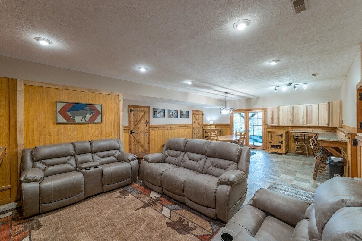 A spacious living area with leather sofas, a wooden accent wall, and a dining area with a wooden table and chairs.