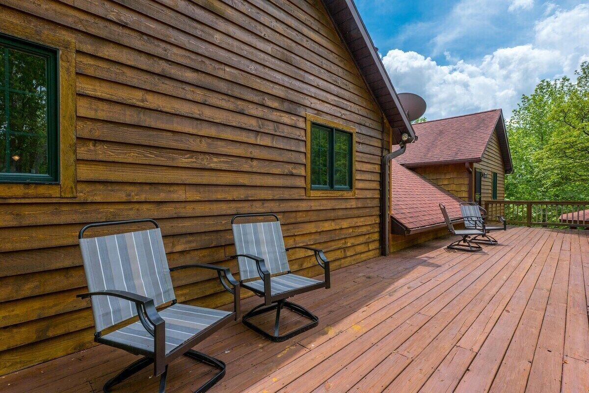 Une cabane en bois avec une terrasse, deux chaises et une antenne parabolique.