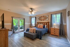 A bedroom with a bed, a nightstand, a dresser, a ceiling fan, and a sliding glass door leading to a patio.