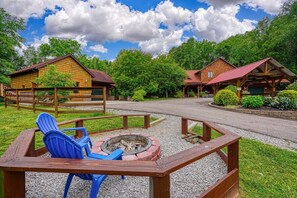 A rustic lodge with wooden cabins, a fire pit, and a gravel path.