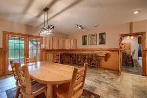 A spacious kitchen with a large wooden dining table and chairs, wooden cabinets, and a built-in island with seating.