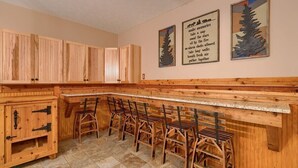 Une cuisine en bois avec un coin bar, des carreaux de pierre et deux citations encadrées accrochées au mur.