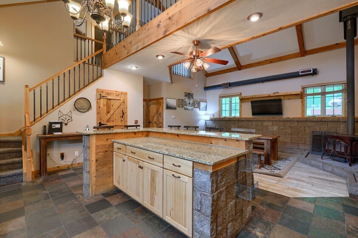 Un'ampia cucina con un'isola grande, mobili in legno e una parete a schiena di pietra.