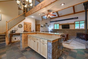 A spacious kitchen with a large island, wooden cabinets, and a stone backsplash.