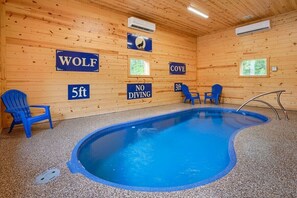 A wooden cabin with a pool, blue chairs, and signs indicating 'WOLF', '5ft', 'COVE', and 'NO DIVING'.