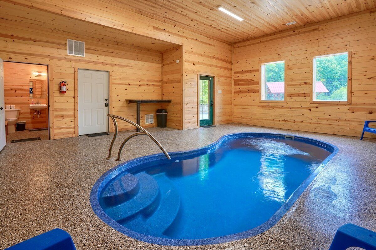 Une cabane en bois avec une piscine, une salle de bain et une table avec une chaise.