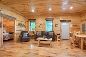 Een houten cabin met een bank, fauteuil, salontafel en eettafel.
