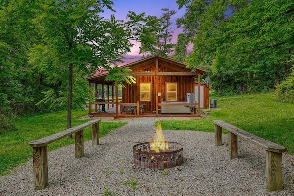 Eine rustikale Holzhütte mit einem Feuerkorb in der Mitte, umgeben von Holzbänken.