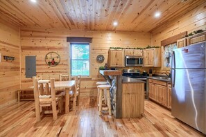 Ein Holzblockhaus-Innenraum mit Essbereich, Küche und einem großen Kühlschrank.