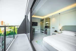 Une chambre d’hôtel moderne dotée d’un balcon, d’un lit, d’un bureau et d’une télévision.