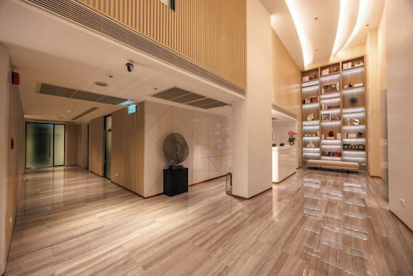 Un hall d’hôtel moderne avec un plancher en bois poli, un comptoir d’accueil et une présentation de divers objets.