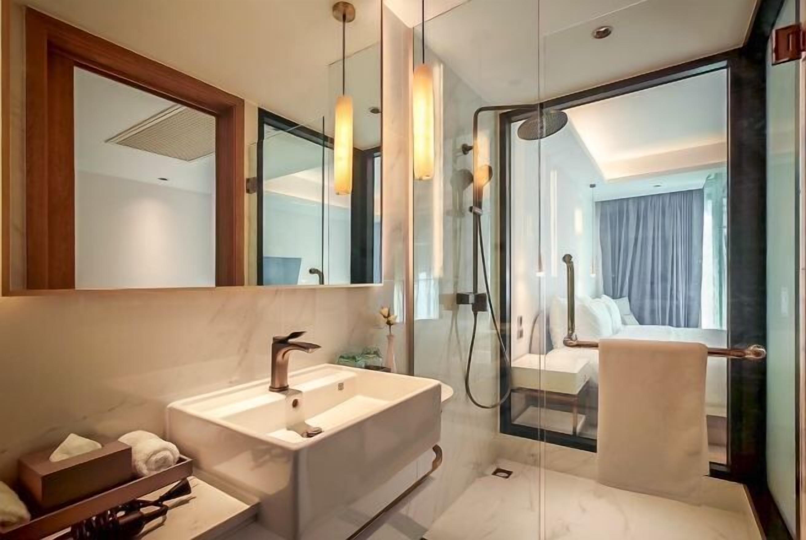 A modern bathroom with a large mirror, a white sink, and a glass-enclosed shower area.