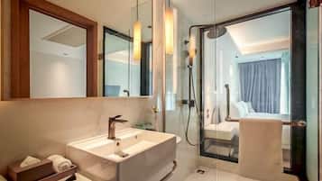 A modern bathroom with a large mirror, a white sink, and a glass-enclosed shower area.