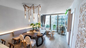 Ein modernes Wohnzimmer mit Essbereich, großen Fenstern und einem Balkon mit Pflanzen.