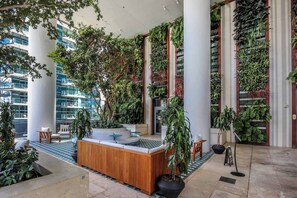 A lobby with a wooden reception desk, seating area, and vertical gardens.