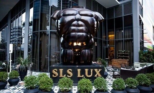 A modern building with a large bronze sculpture of a muscular figure in front.