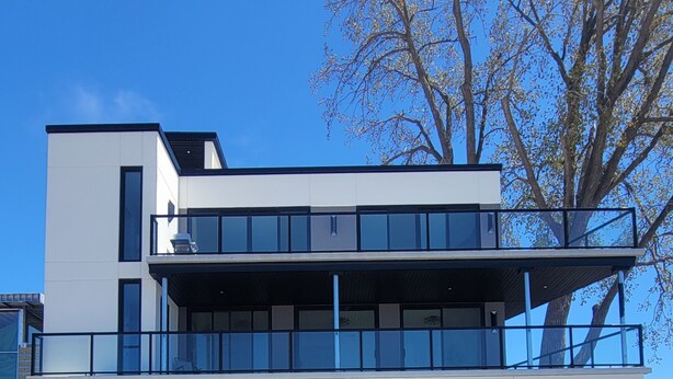 Un immeuble moderne à deux étages, doté de grandes fenêtres et d’un balcon.