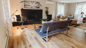 A modern living room with a fireplace, a blue sofa, a coffee table, and a dining area with a table and chairs.