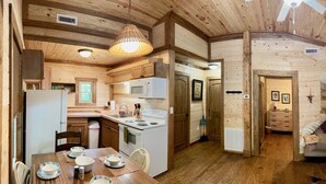 A wooden cabin interior with a kitchen, dining area, and a living room. - Charming 2-bedroom cabin in beautiful mountains of Pickens, SC. (Pickens)