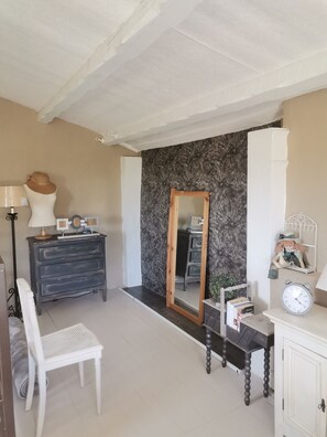Cozy retreat with a large mirror, dresser, and comfortable chair, set against a floral wallpaper backdrop.