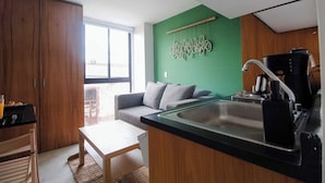 Cozinha compacta com bancada preta, pia e cafeteira.