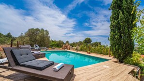Un espace aménagé au bord de la piscine, avec des chaises longues et un mur en pierre.